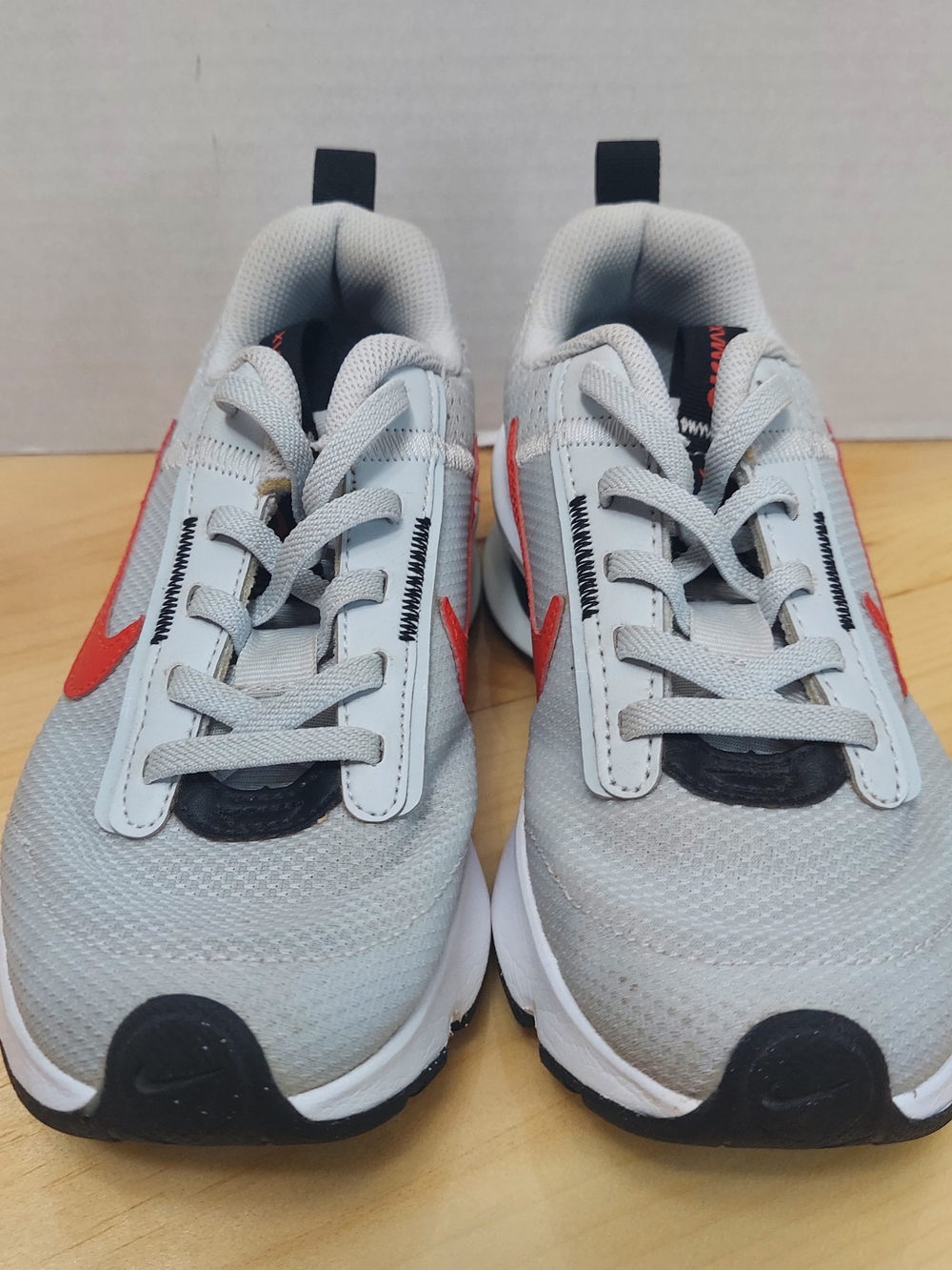 The Nike Air Max INTRLK Lite kids' sneakers, highlighted by a vibrant red Swoosh